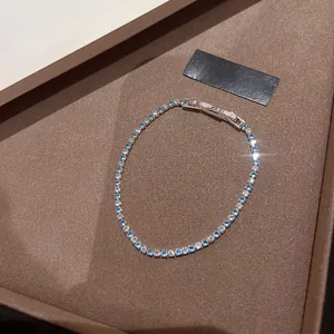 Detail view of silver-tone tennis bracelet with lake blue and clear cubic zirconia stones.