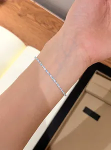 Close-up of a delicate silver bracelet with blue and clear zircons on a female wrist.