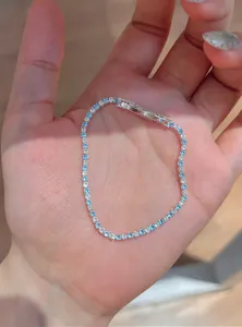 Detailed close-up view of a light blue and clear zircon tennis bracelet held in a palm