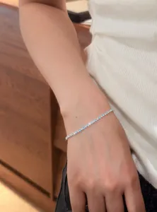 Elegant thin tennis bracelet with light blue and clear zircons on a female wrist