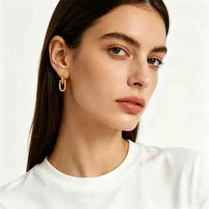 Primer plano de pendientes de cadena en U bañados en oro de 18K en modelo, estilo ins.
