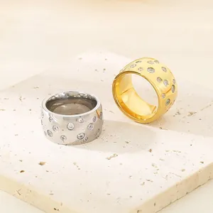 Wide titanium steel rings with scattered crystal settings in gold and silver finish.