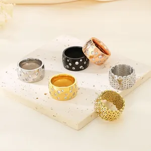 Detail view of wide band titanium steel rings with scattered rhinestones and hollow patterns.
