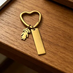 Gros plan d'un porte-clés doré en forme de cœur avec breloque fille et plaque
