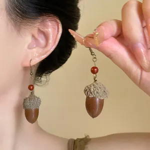 Vintage acorn drop earrings featuring realistic nut pendants and red beads on model