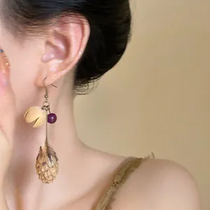 Detail view of vintage ethnic earrings with a metallic pinecone pendant and purple bead.