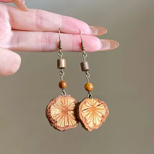 Detail view of retro ethnic drop earrings featuring natural wood slices and metal hooks