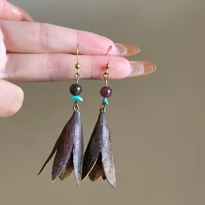 Close-up detail of vintage metal pinecone pendant earrings with turquoise beads