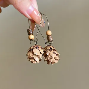 Detailed close-up of vintage bronze pinecone earrings featuring natural wooden beads
