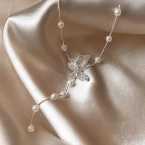 Elegante Halskette mit Schmetterlingsanhänger und Perlen auf champagnerfarbenem Satin.