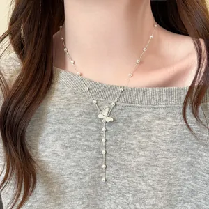 Detailansicht einer zarten Schmetterlingskette mit eleganten Perlen an einem Modell.