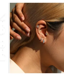 Gros plan de clous d'oreilles en argent sterling S925 et moissanite sur l'oreille d'un modèle
