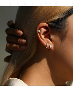 Détail macro de clous d'oreilles en moissanite couleur D et argent S925 portés sur l'oreille.