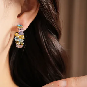 Close-up of colorful zircon oval hoop earrings worn on ear with silver needle