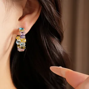 Detailed close-up showing colorful oval zircon earrings worn on a model's ear lobe.