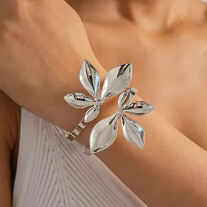 Detailansicht eines polierten silbernen Blatt-Doppelschicht-Armreifs am Arm des Models.
