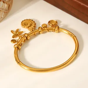 Detailed close-up of 18K gold-plated bangle with sea star and shell charms.