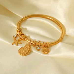 Close-up of 18K gold-plated stainless steel bangle with starfish and shell charms