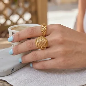 Détail de style d'une bague unique en maille dorée ajourée portée par une femme