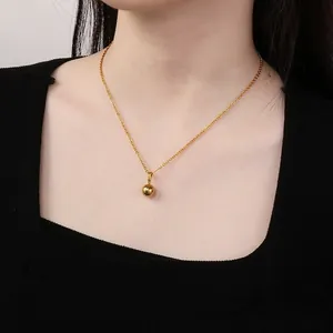 Detailed view of a minimalist gold solid mirror ball pendant necklace worn by a model