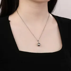 Detailed view of a minimalist silver mirror ball pendant on a stainless steel chain