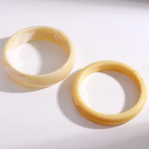 Detailansicht von zwei cremefarbenen Marmor-Resin-Armreifen mit poliertem Finish