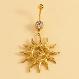Detail of golden stainless steel belly button ring with swirl sunburst pendant and crystal.