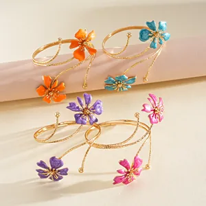 Dettaglio di bracciali da braccio in metallo con fiori smaltati colorati assortiti