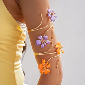 Dettaglio di un bracciale da braccio dorato con fiori in smalto viola e arancione