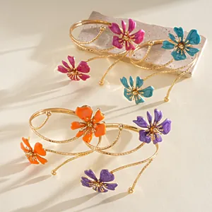 Primo piano di bracciali da braccio in metallo con fiori in smalto colorato e oro lucido.