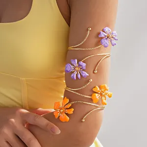 Dettaglio di un bracciale a spirale dorato con fiori in smalto viola e arancione.