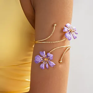 Dettaglio di un bracciale da braccio a fiore dorato con petali in smalto viola su modella.