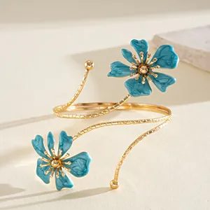 Vista dettagliata di un elegante bracciale da braccio in metallo dorato con fiori smaltati.