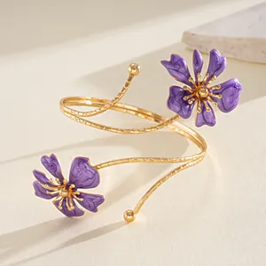 Dettaglio di un bracciale a spirale dorato con fiori in smalto viola