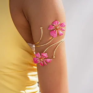 Primo piano di un elegante bracciale da braccio in oro con due fiori di smalto rosa
