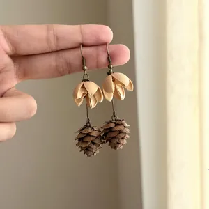 Macro view of Maillard-style dangle earrings featuring natural pinecone and pod details.
