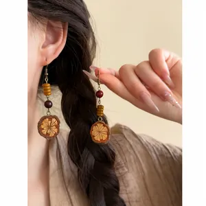 Detailed macro view of unique ethnic style Maillard wood fruit beaded fringe earrings.