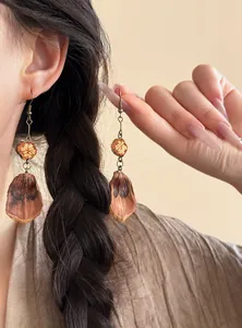 Detail of Maillard style fruit earrings with dried orange and petal dangles on bronze hooks.