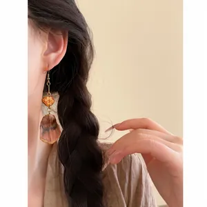 Detailed view of Maillard style ethnic fruit beaded tassel earrings worn by a model