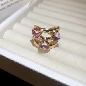 Close-up of a high-end gold ring featuring three sparkling pink triangular gems