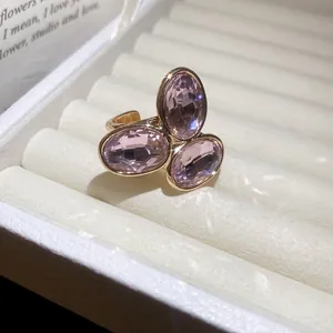 Detailed close-up of a vintage gold-toned open ring featuring three oval pink crystals