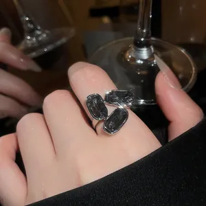 Close-up of elegant silver ring with three oval black gemstones on model's finger.