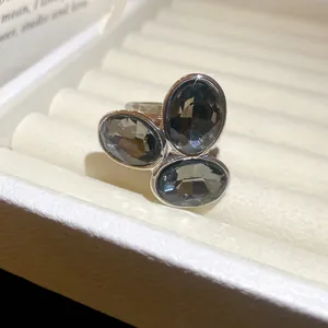 Detailed close-up of a vintage-style open ring with three oval grey stones
