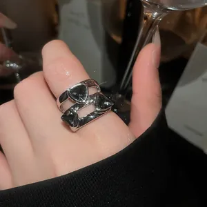 Close-up view of an elegant silver open ring featuring three black triangular gemstones.