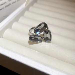 Detailed close-up of elegant silver open ring featuring three sparkling grey faceted stones