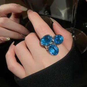 Close-up of a vintage-style ring featuring three sparkling blue oval gemstones