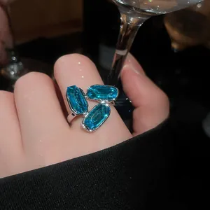 Macro close-up detail of a silver ring with three oval blue gemstones on a finger