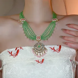 Nahaufnahme einer mehrlagigen grünen Perlenkette im Vintage-Palaststil mit Kristallanhänger.