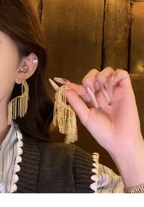 Exquisite detailed view of gold geometric twisted tassel earrings worn by a model
