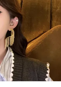 Macro detail of exaggerated gold geometric tassel earrings worn for a high-end look